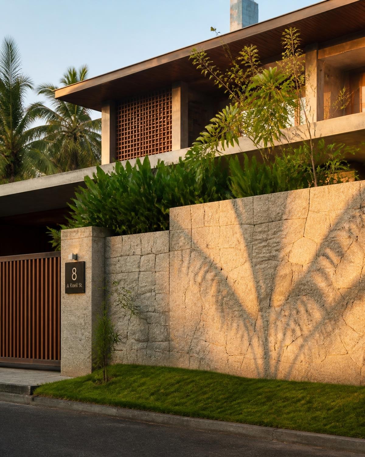 A South Indian home behind a dressed granite compound wall in late afternoon light